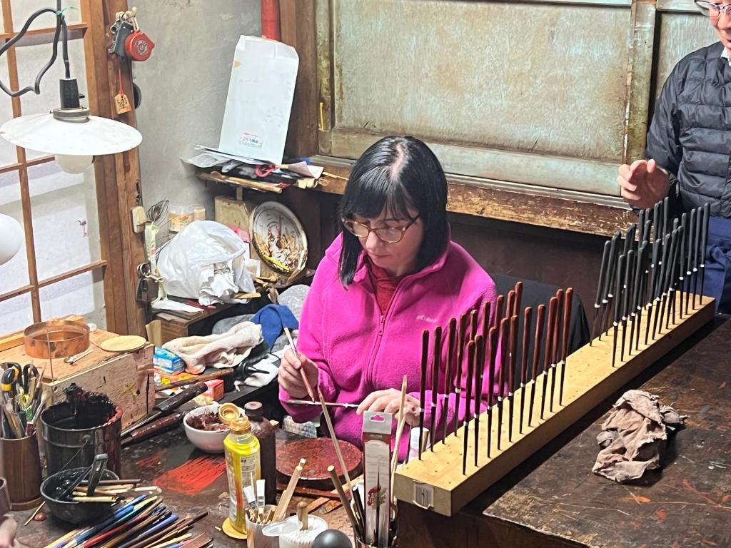 A guest applying lacquer to chopsticks during the workshop